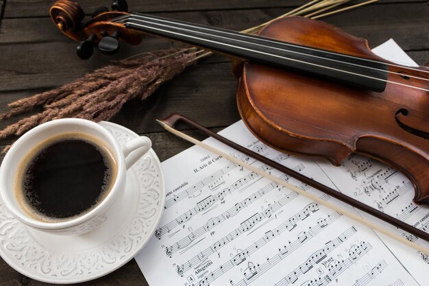 Composition avec violon tasse de café et partitions sur table en bois