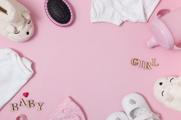 Composition vue de dessus avec accessoires pour bébés et vêtements sur une surface rose colorée