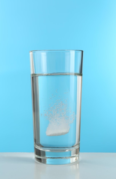 Comprimé dans un verre d'eau sur fond bleu