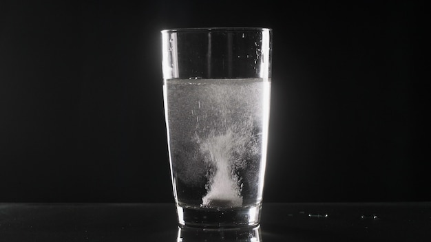 Comprimé effervescent blanc en verre avec de l'eau sur la table