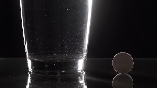 Comprimé effervescent blanc en verre avec de l'eau sur la table