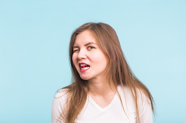 Comprimé rouge dans la bouche de la femme sur le mur bleu