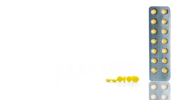 Comprimés pelliculés jaunes comprimés sous blister et groupe de comprimés ronds jaunes comprimés sur blanc