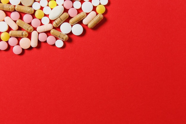 Les comprimés ronds colorés blancs de médicament ont arrangé le résumé sur le fond de couleur rouge