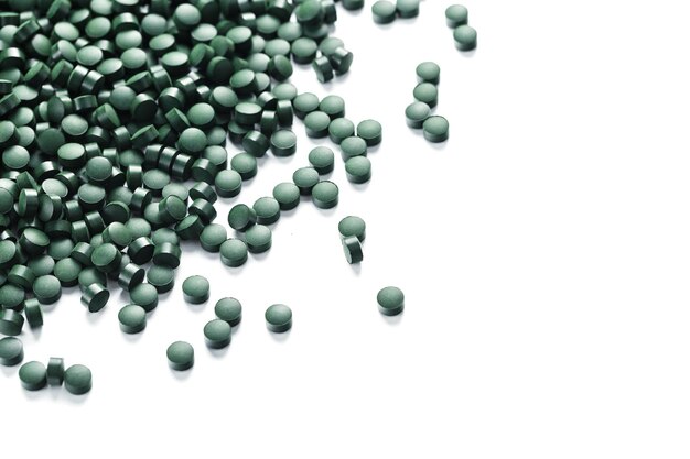 Comprimés verts à base de spiruline biologique naturelle sur fond blanc avec espace libre