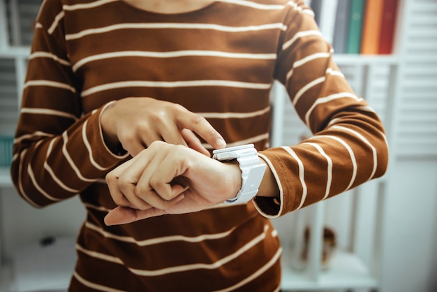 Comptable à la recherche de temps à portée de main montres dans un bureau moderne rêver de vacances le week-end en profitant de la vue depuis la fenêtre.