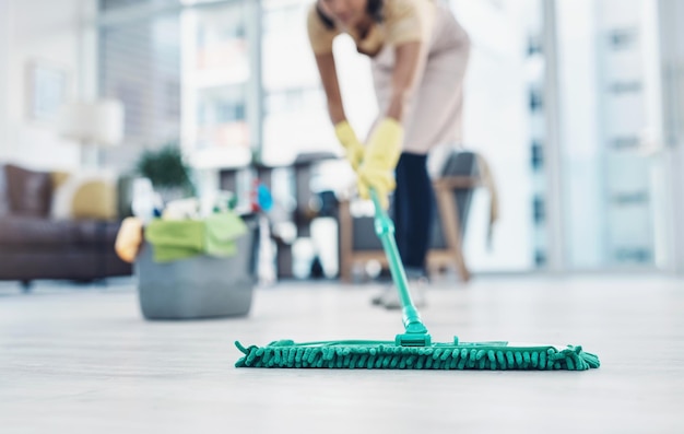 Le compte à rebours pour nettoyer les sols brillants Photo d'une femme méconnaissable passant la serpillière à la maison
