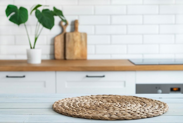 Comptoir blanc en bois avec serviette et espace libre pour le montage d'un produit ou d'une mise en page sur le fond d'une cuisine blanche floue avec plante monstera