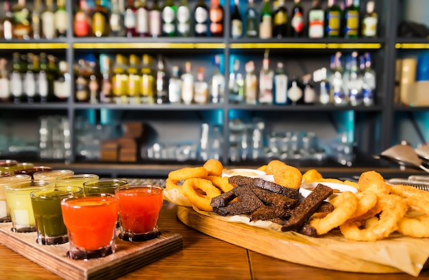 Sur le comptoir du bar, il y a un ensemble de diverses teintures et une assiette avec des collations des rondelles d'oignon des bâtonnets de fromage des boules et des croûtons