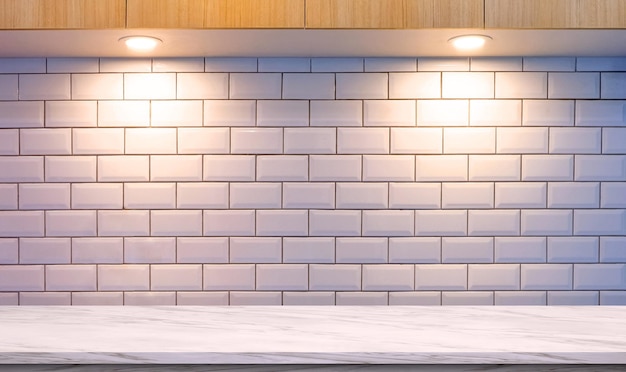 Comptoir en marbre blanc avec des lampes LED éclairant le mur en carreaux et l'armoire murale en bois dans une cuisine moderne