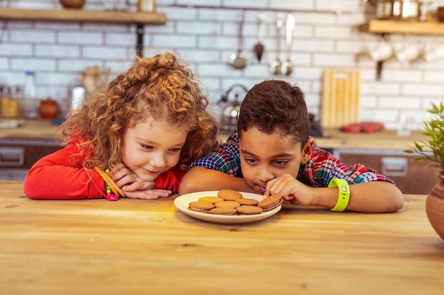 Comptons. Enfants joyeux regardant des biscuits en allant les manger après le dîner