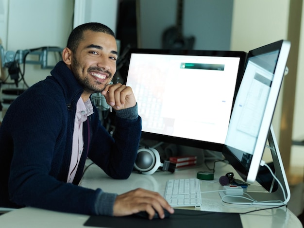 Computer screen portrait and smile of programmer at desk in office for coding or web development Business design and internet with happy programming employee in workplace at night for deadline