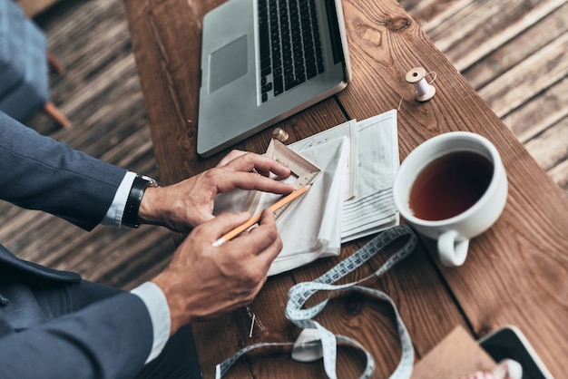 concentré au travail. gros plan sur la vue de dessus du créateur de mode faisant des croquis