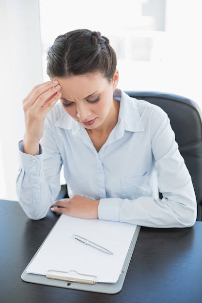 Concentré élégante femme brune en regardant son presse-papiers