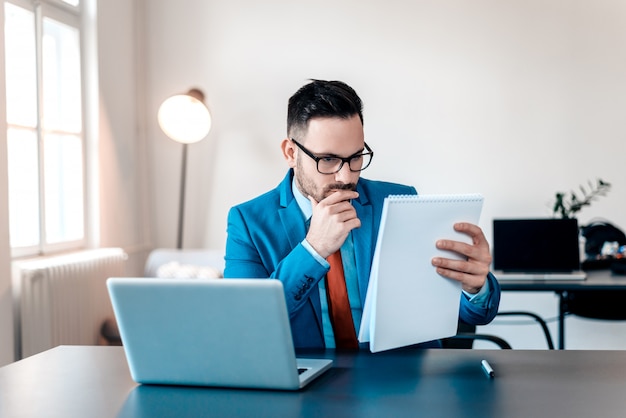 Concentré jeune homme d&#39;affaires, lecture de documents au bureau.