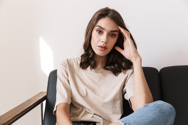 concentré jolie jeune femme sérieuse incroyable posant à l'intérieur à la maison sur le canapé.