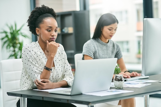 Concentré sur leur travail Photo recadrée de deux jeunes femmes d'affaires travaillant à leur bureau au bureau