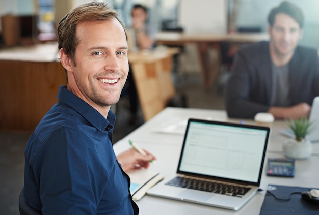 Concentré sur le succès et s'amusant à le faire Portrait d'un designer travaillant sur un ordinateur portable dans un bureau