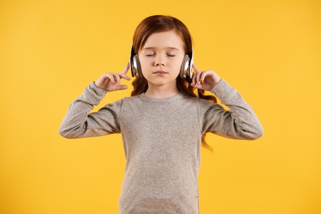 Concentrée petite fille au casque écoute les classiques.