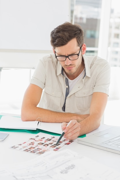 Concentrer l&#39;artiste masculin assis au bureau avec des photos