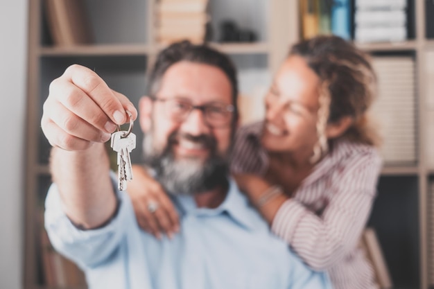 Concentrez-vous sur les clés détenues par les jeunes conjoints enthousiastes propriétaires Heureux couple de famille marié célébrant le déménagement dans une nouvelle maison démontrant les clés debout dans un concept d'hypothèque immobilière d'appartementxA