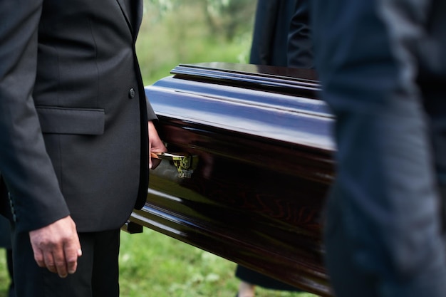 Concentrez-vous sur l'homme en costume noir tenant par la poignée d'un cercueil en bois