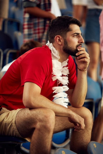 Concentrez-vous sur un jeune homme concentré dans un stade qui assiste à un match de football pour remonter le moral de son équipe favorite