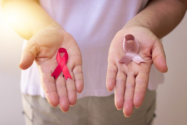 Concentrez-vous sur une main mûre tenant un ruban rose isolé sur blanc. Image du Mois de la sensibilisation au cancer du sein.