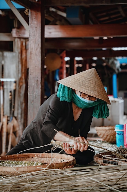 Concentrez-vous sur une vieille femme avec une robe traditionnelle vietnamienne ao ba ba Faire de l'emballage du gâteau du Têt le nouvel an lunaire vietnamien de la nourriture du Têt en plein air à la main