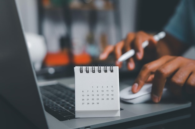 Concept 2022 Calendrier papier placé sur la table de bureau avec l'ordinateur portable de l'homme d'affaires