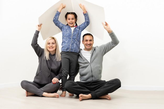 concept abritant une jeune famille. Mère père et enfant dans une nouvelle maison avec un toit au mur de briques vides.