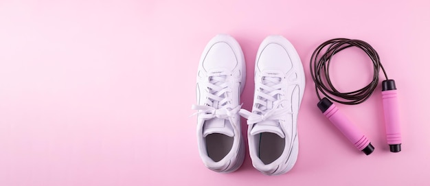 Concept d'accessoires de fitness Vue de dessus photo de baskets blanches et corde à sauter fond rose