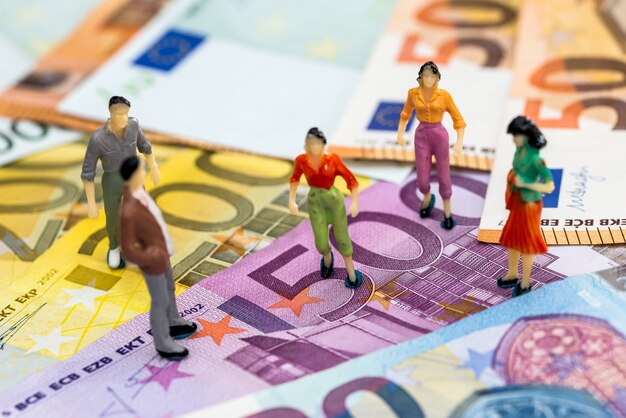 Concept d'accord financier - personnes miniatures sur les billets en euros