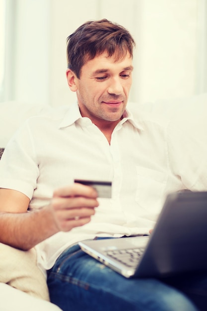 concept d'achat en ligne ou sur Internet - homme souriant avec ordinateur portable et carte de crédit à la maison