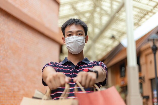 Concept d'achat Le mâle ayant son masque sur son visage essayant la main beaucoup de son sac à provisions