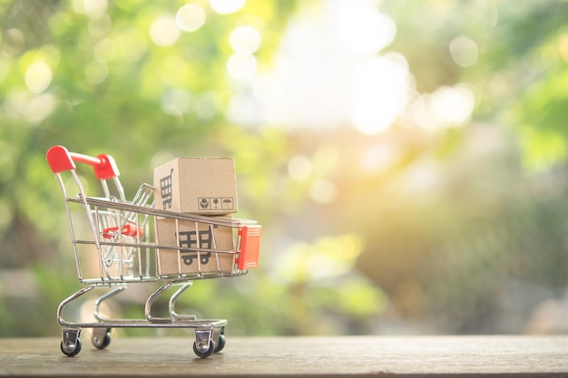 Concept d'achat Panier d'achat ou chariot et cartons de papier ou colis avec un logo de panier d'achat sur une table en bois.