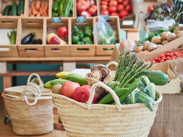 Concept d'achat sain et durable Panier en osier plein de légumes et de fruits dans un petit magasin d'aliments biologiques locaux En arrière-plan des étagères avec d'autres produits dans des caisses en bois