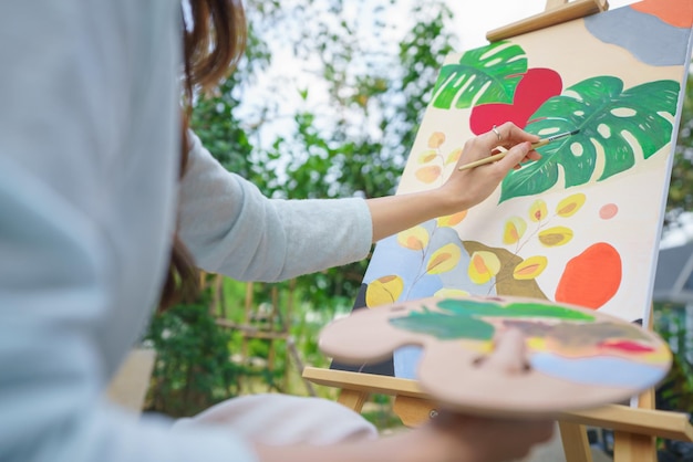 Concept d'activité de plein air Artiste féminine peignant sur toile avec pinceau et aquarelle dans le jardin