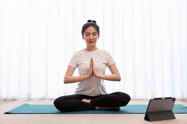 Concept d'activité productive une jeune femme adulte fermant les yeux en mettant ses mains sur le tapis vert dans la pièce calme.