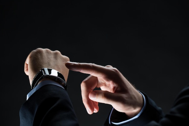 concept d'affaires, de personnes et de technologie - gros plan des mains d'un homme d'affaires avec une montre intelligente sur le noir