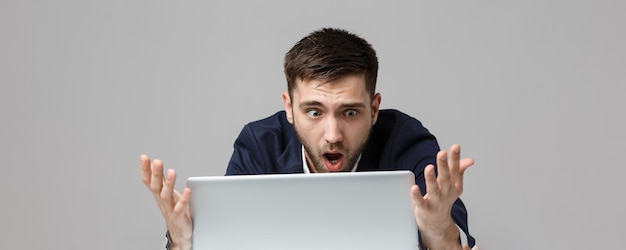 Concept d'affaires Portrait bel homme d'affaires stressant en costume de choc regardant au travail dans un ordinateur portable Fond blanc