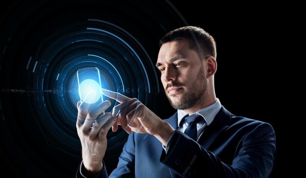 concept d'affaires, de réalité augmentée et de technologie future - homme d'affaires en costume travaillant avec un smartphone transparent et un hologramme sur fond noir