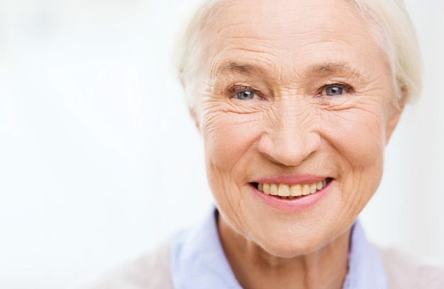 Photo concept d'âge et de personnes - visage de femme âgée souriante et heureuse à la maison