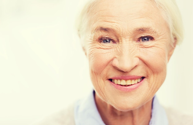 concept d'âge et de personnes - visage de femme âgée souriante et heureuse à la maison