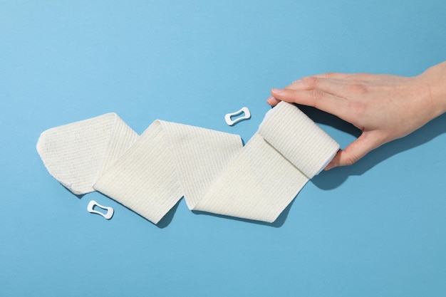 Concept d'aide lors d'une blessure main féminine et bandage élastique sur fond bleu