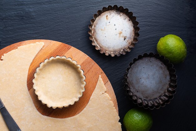 Concept alimentaire Croûte à tarte vide maison pour citron, tartes au citron vert ou mini tarte sur ardoise noire