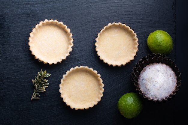 Concept alimentaire Croûte à tarte vide maison pour citron, tartes au citron vert ou mini tarte sur ardoise noire