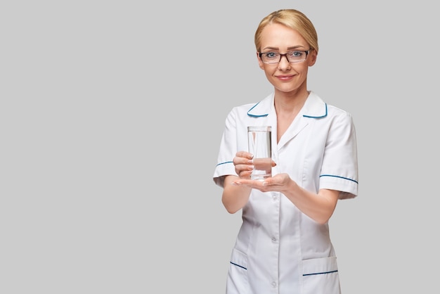 Concept d'alimentation ou de mode de vie sain - femme médecin tenant et un verre d'eau douce claire