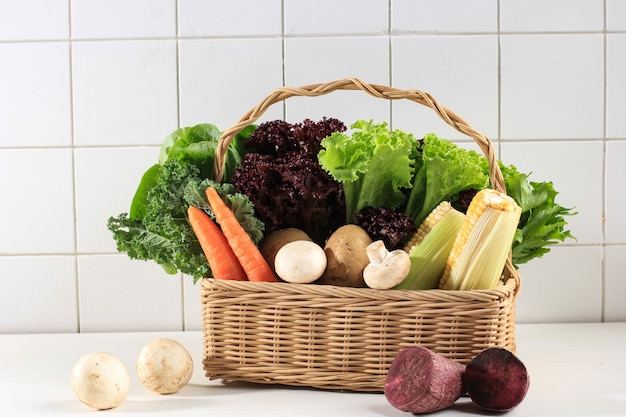 Concept d'alimentation saine, diverses feuilles de légumes frais sur un panier. Copiez l'espace. Chou frisé, laitue, laitue mauve, endive, carotte, champignon, maïs, patate douce puplre, pomme de terre