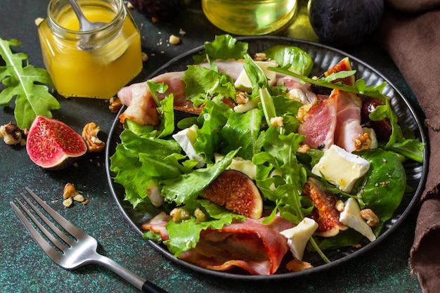 Concept d'alimentation saine salade d'automne aux figues prosciutto roquette épinards fromage noix et miel